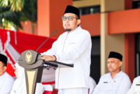Foto: Bupati Sumenep Achmad Fauzi Wongsojudo mengenakan busana santri serba putih lengkap dengan peci hitam saat menyampaikan pidato pengarahan Hari Santri Nasional 2026 di halaman Kantor Bupati Sumenep.